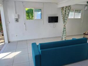 a living room with a blue couch and a tv at HELICONIA rostrata in Sainte-Rose