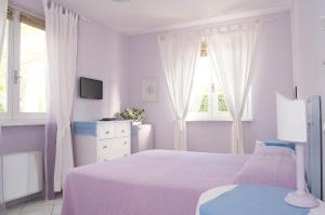a white bedroom with a bed and two windows at Villa Amelia Rooms in Marina di Pietrasanta