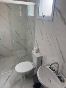 a white bathroom with a toilet and a sink at Flats e Residence - Apartamento novo in Passo Fundo