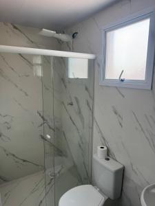 a white bathroom with a toilet and a window at Flats e Residence - Apartamento novo in Passo Fundo