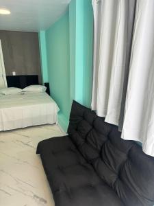 a bedroom with two beds and a couch in front of a window at Flats & Residence - Apart 105 in Passo Fundo