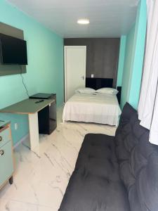 a bedroom with a bed and a desk and a couch at Flats & Residence - Apart 105 in Passo Fundo
