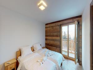 a bedroom with two beds and a large window at Duplex apartment in Veysonnaz in Veysonnaz