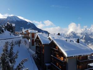 a building covered in snow with mountains in the background at Family apartment with terrace in Veysonnaz