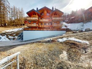 a large wooden house with a fence in front of it at Centrally-located apartment for 6 in Veysonnaz