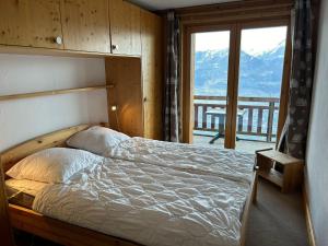 a bedroom with a bed with a view of a mountain at Pleasant apartment with balcony in Veysonnaz