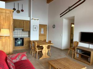 a living room with a wooden table and a kitchen at Pleasant apartment with balcony in Veysonnaz