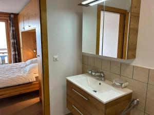 a bathroom with a sink and a mirror and a bed at Pleasant apartment with balcony in Veysonnaz