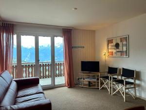 a living room with a couch and a television and a balcony at Apartment in Veysonnaz with balcony in Veysonnaz