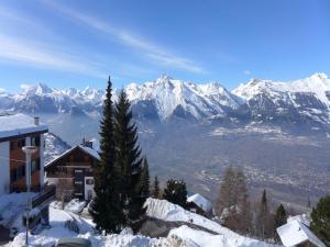 a snow covered mountain range with a house and a tree at Apartment in Veysonnaz with Mountain Views in Veysonnaz +9 photos