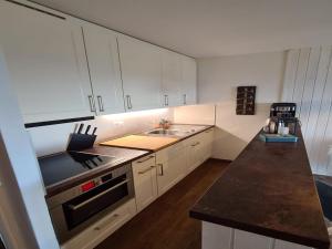 a kitchen with white cabinets and a sink and a stove at Flat in Veysonnaz near Ski Lift & Valley Views in Veysonnaz