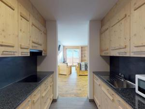 a kitchen with wooden cabinets and black counter tops at Pleasant apartment in Versonnaz in Veysonnaz +28 photos