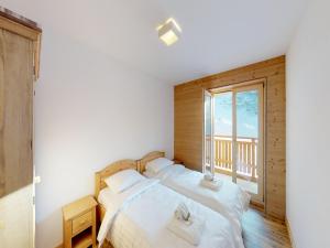 two beds in a room with a window at Pleasant apartment in Versonnaz in Veysonnaz