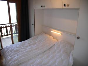 a white bed in a room with a window at Mountain apartment with parking in Veysonnaz