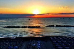 einen Sonnenuntergang über dem Meer mit einer Straße im Wasser in der Unterkunft Appartamenti Romita in Cupra Marittima