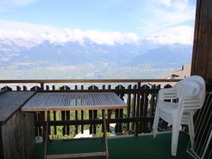 a table and a chair on a balcony with mountains at Studio in Veysonnaz near Ski Lift in Veysonnaz