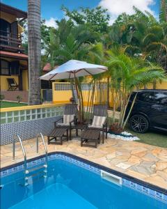 a pool with a table and an umbrella and a car at Casa em Ilhabela - Próxima à Praia do Curral in Ilhabela