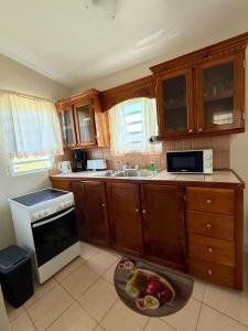 a kitchen with wooden cabinets and a plate of food on the floor at Hill Top Cottage in Friar's Bay +5 photos