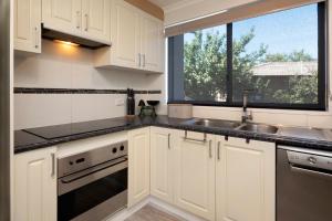 a kitchen with white cabinets and a sink and a window at Aalen Lakeview Suite in Jindabyne