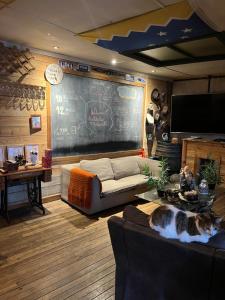 un gato sentado en un sofá en una habitación con una pizarra en Hostel La Morenita, en Punta Arenas