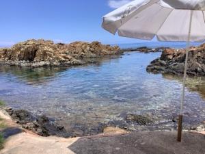 a white umbrella sitting on a beach near the water at Magique Creek, piscine naturelle dans les rochers in Zonza +14 photos