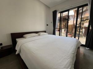 Un dormitorio con una gran cama blanca con una gran ventana. en Uger House Seminyak, en Seminyak