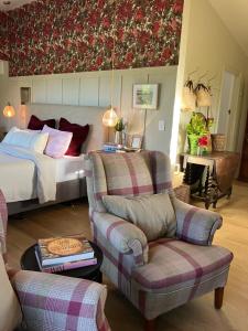 a bedroom with a bed and a couch and chairs at Gate Keepers Cottage in Tasman