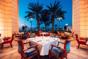 a restaurant with tables and chairs and palm trees at The Ritz-Carlton Jeddah in Jeddah
