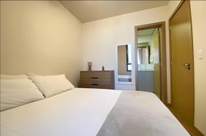 a bedroom with a large white bed and a door at Central, Ar Cond, WI-FI, Lava e Seca in Santa Maria