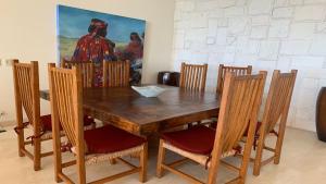 einen hölzernen Esstisch mit Stühlen und ein Gemälde in der Unterkunft Encanto Living Penthouse 1202 by Kivoya in Playa Encanto
