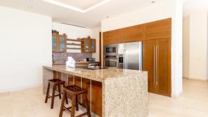 eine Küche mit Granitarbeitsplatte und Holzschränken in der Unterkunft Encanto Living Penthouse 1202 by Kivoya in Playa Encanto