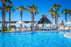 einen Pool mit Palmen, Stühlen und Sonnenschirmen in der Unterkunft Encanto Living Penthouse 1202 by Kivoya in Playa Encanto