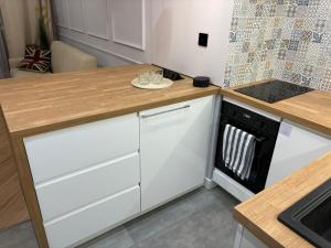 Apartament centrum في بياويستوك: مطبخ بخزائن بيضاء وطاولة خشبية +صورة واحدة