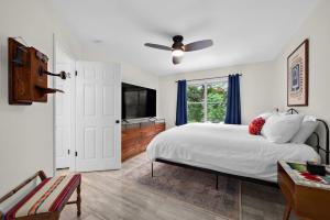 Un dormitorio con una cama y un televisor y una ventana. en Artist Retreat on the Creek - Sleeps 10 - Hot tub, en Leander