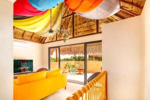 a living room with a yellow couch and colorful ceiling at Zambo in Tulum