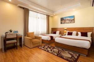 um quarto de hotel com duas camas e uma cadeira em Magnificent Hotel em Catmandu