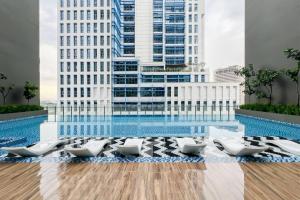 a pool with white lounge chairs in front of a building at Alinea Luxury Condominiums, Shah Alam - Smarthome in Shah Alam