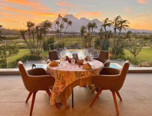 a dining table with chairs and a view of a pool at Ludus Magnus Boutique Hotel in Franschhoek