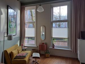 a living room with windows and a yellow couch at Logies Reederij de IJsel in Gouda