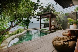 a wooden deck with a pool and a gazebo at AKSARA Nusa Penida Private Villa in Nusa Penida
