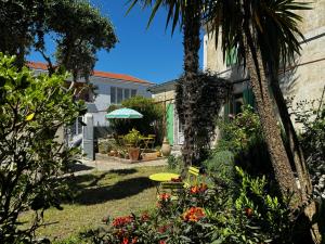 un jardin avec un palmier et une maison dans l'établissement Charmante Maison Familiale - Grande Capacité, à Saint-Laurent-de-la-Prée