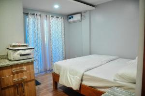 a bedroom with a bed and a dresser and curtains at Dos Marias Tourist Inn in Daanbantayan
