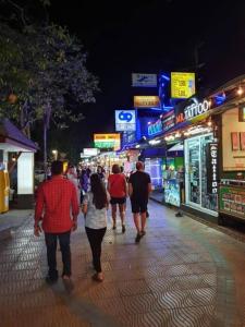 a group of people walking down a street at night at Chicago lanta in Phra Ae beach