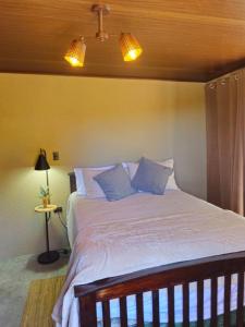 a bedroom with a bed with white sheets and blue pillows at Hacienda Tierra de Fuego Pacaya in Escuintla