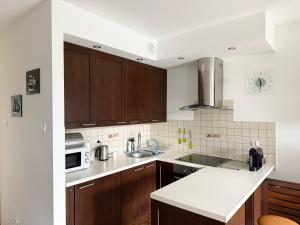 kuchnia z brązowymi szafkami i białym blatem w obiekcie APARTAMENT POD GWIAZDAMI, z dwoma ogródkami i dwoma tarasami w Polanicy Zdroju