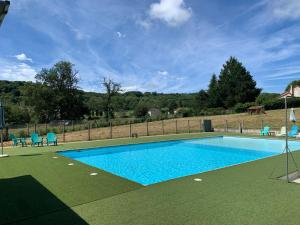 a swimming pool with blue chairs and a fence at Le Petit Bois 46 in Leyme