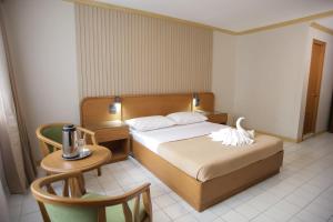 a bedroom with a bed and a table and a chair at Hotel Soriente in Manila