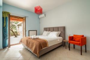 a bedroom with a bed and a orange chair at Nidri Hills Villa in Nydri