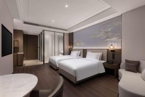 a hotel room with two beds and a table at Wyndham Garden Xunyang Downtown in Xunyang +12 photos