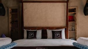a bedroom with a bed with a wooden headboard and pillows at the suwgra-Al-Jabal Al-Akdar in Sūkirah